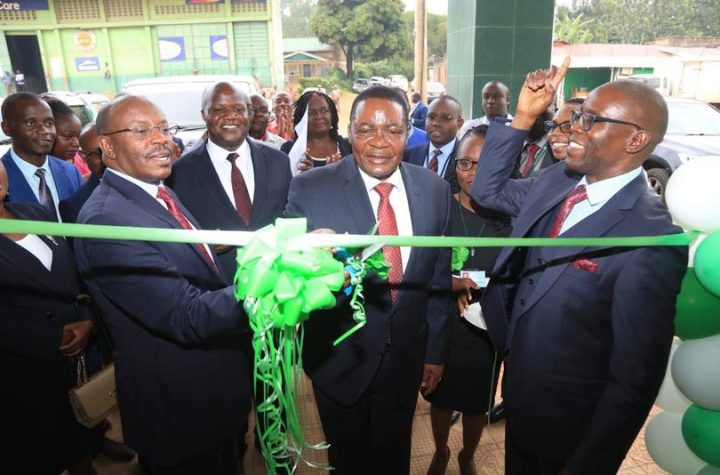 Hon. Kenneth Marende, Former Speaker of the National Assembly assisted by Mr. Peter Kirugu, Head Branch Banking, cuts the ribbon to mark the opening of the Luanda Branch. Others in the picture are Mr. Paul Chianda, Regional Manager, Western Region and Mr. Patrick Ndumbi, Branch Manager Luanda Branch.